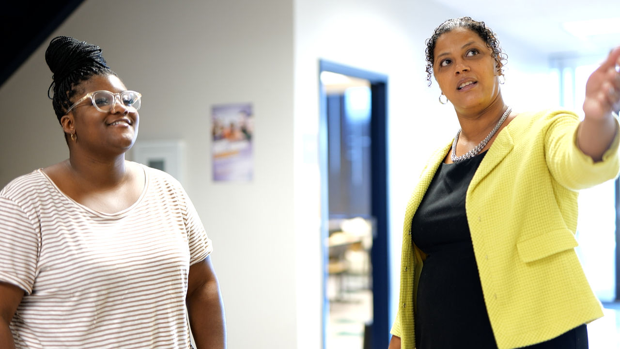 Two women conversing in modern office hallway