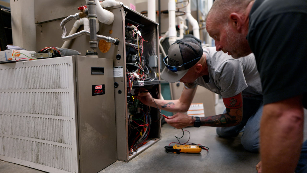 Technicians repairing HVAC system in workshop