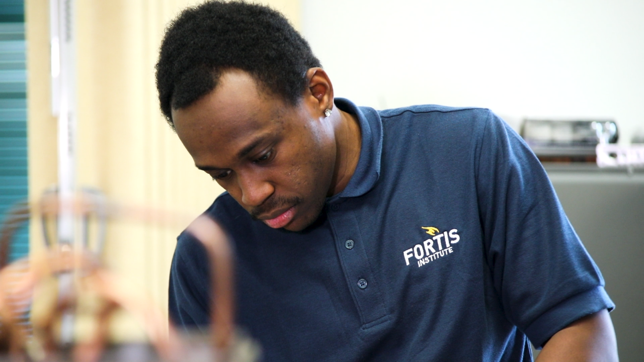 Student in Fortis Institute Polo Shirt at Workstation